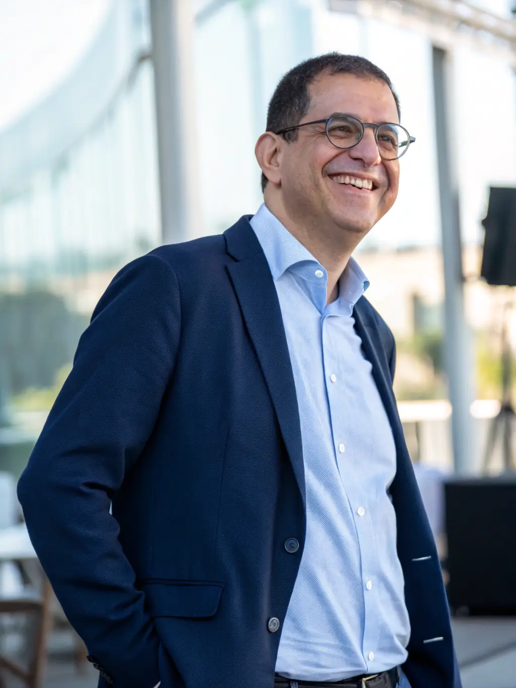 Portrait of a middle-aged French man with short dark hair, wearing a navy suit and white shirt, smiling gently, set against a neutral background, representing the President of the association.